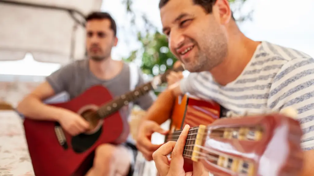 A man playing the guitar with his friend