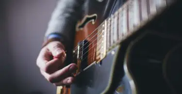 A man playing fingerpick style on his guitar