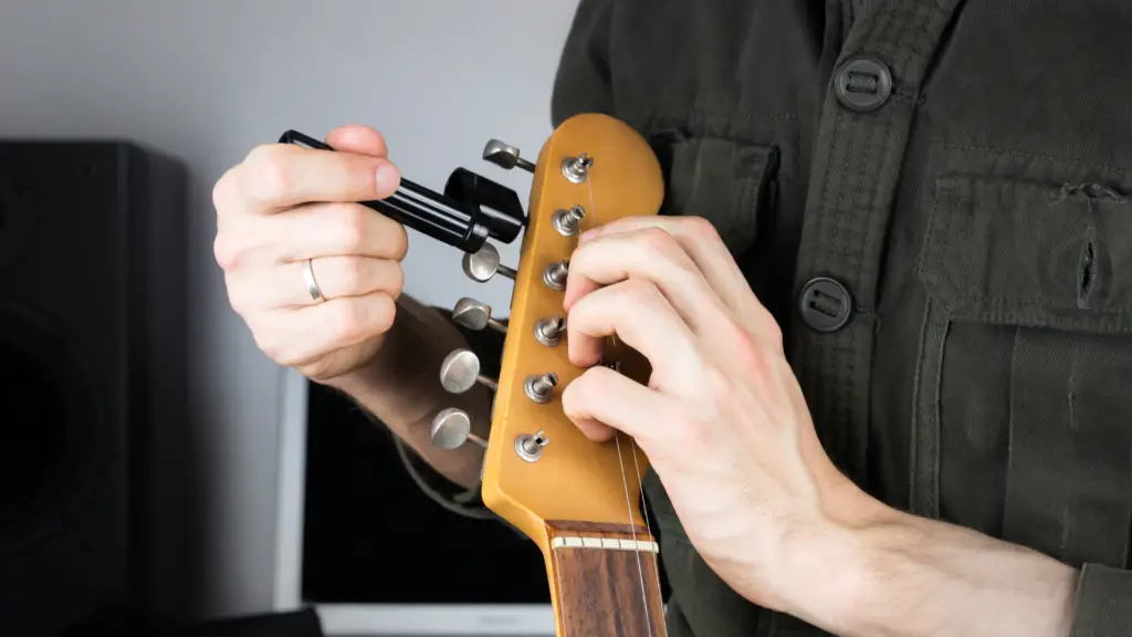 A person using a guitar tuner to tune his guitar