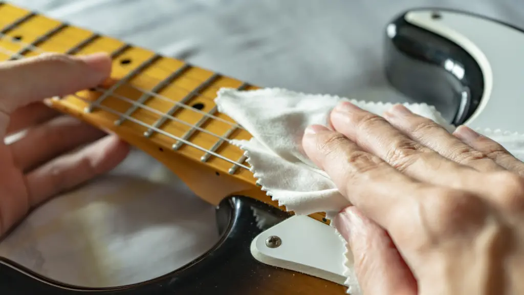 A person wiping an electric guitar with a cloth